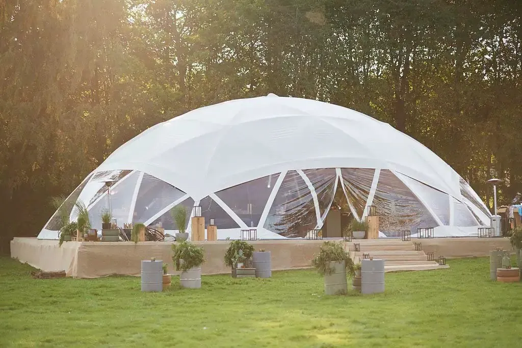 Flat Dome mit transparenten Wänden auf einem Holzpodest im Abendlicht