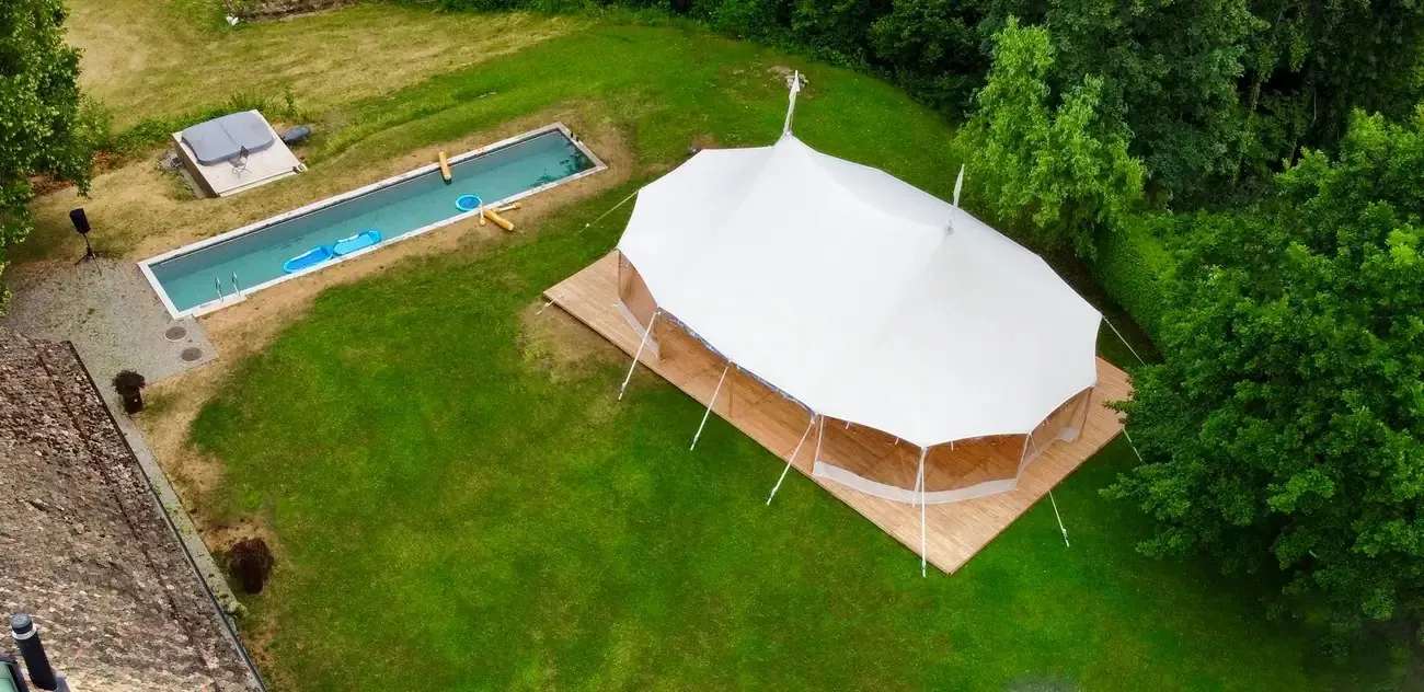 Segeltuchzelt mit Holzboden von oben fotografiert, neben einem Pool