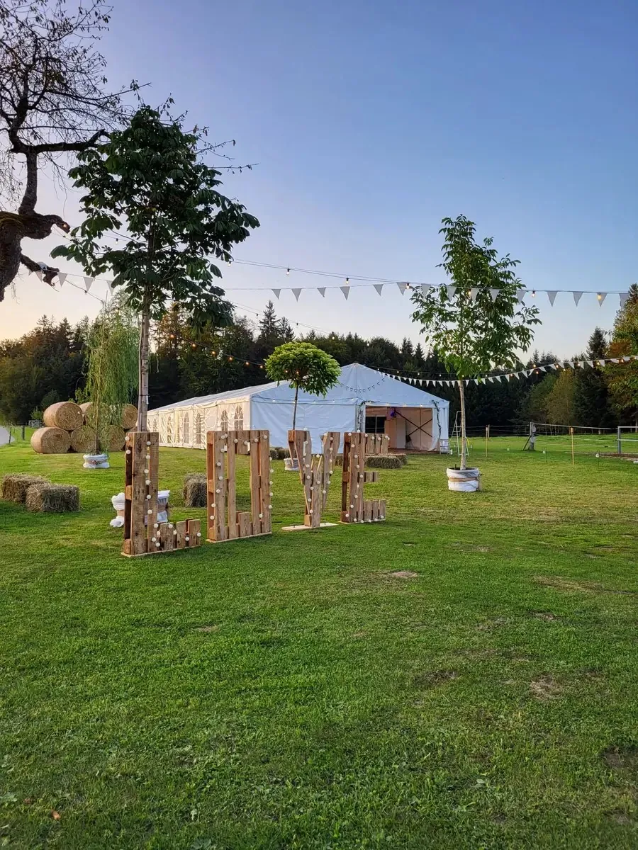 Festzelt auf einer Wiese mit Wimpeln und Holzbuchstaben