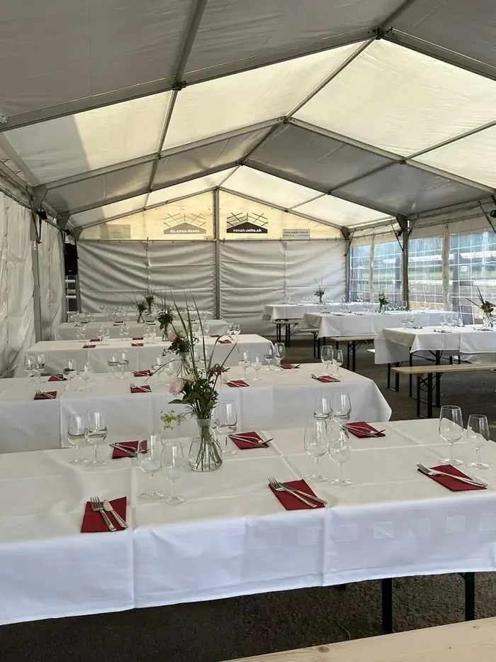 Festlich gedeckte Tische mit Blumen im Partyzelt
