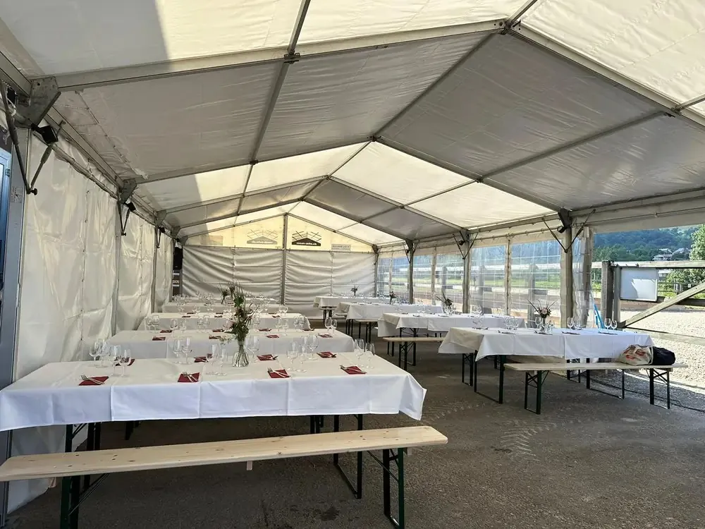 Partyzelt innen mit langen, weiss gedeckten Tischen