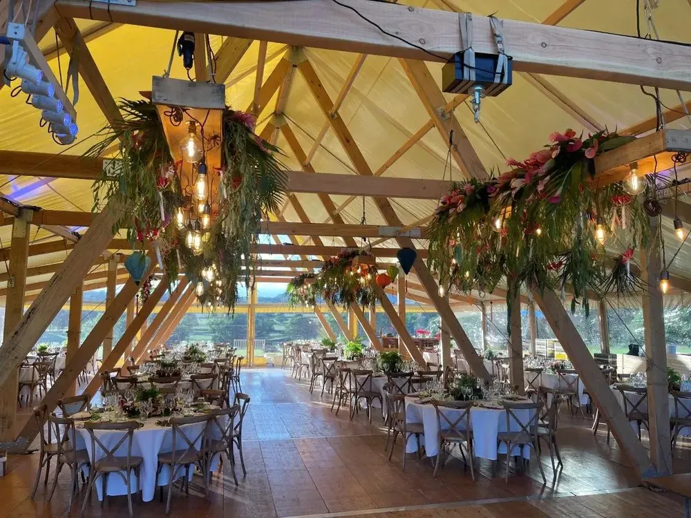 Event Chalet innen mit runden Tischen, Blumen und Holzbalken
