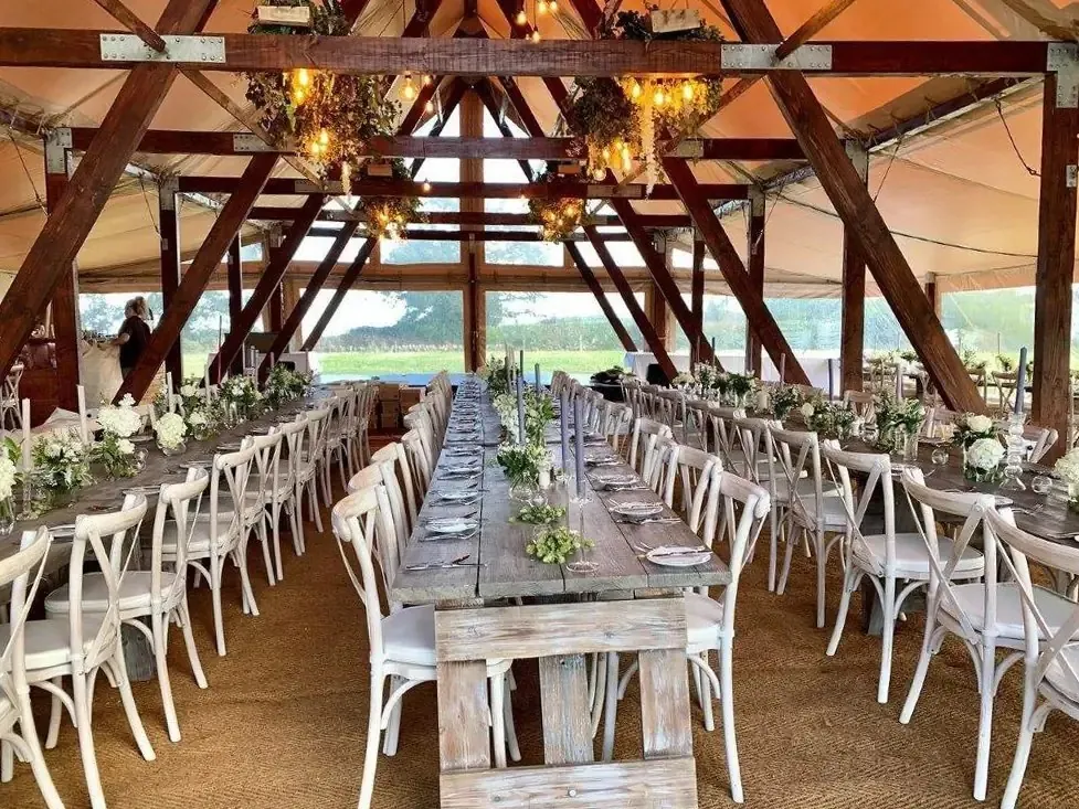 Lange festlich gedeckte Tafel unter dem Holzdach des Event Chalets