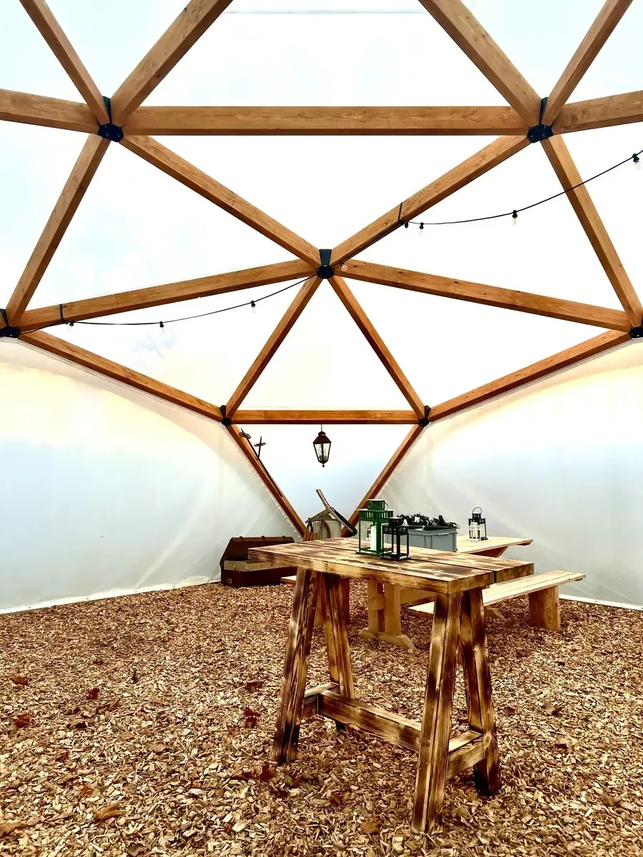 Wood Dome von innen mit Holzbalken, Lichterkette und Holztischen
